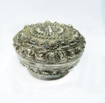 An 8cm diameter old Chinese white metal pot with ornate embossed decoration and push-fit lid -