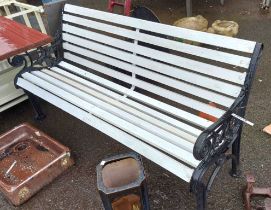 A white painted garden bench with wrought iron ends with a black finish