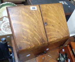 A vintage oak slope front stationery cabinet with letter rack interior enclosed by a pair of