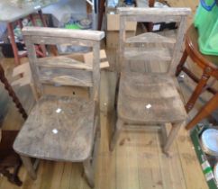 A pair of old stripped wood chapel chairs with moulded solid seats, set on simple turned supports