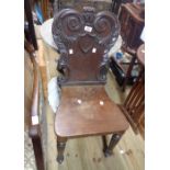 A Victorian mahogany hall chair with ornate carved back and solid seat, set on reeded front legs