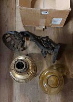 A box containing a brass oil lamp with bulbous amber glass chimney and a cast iron wall mouted plant