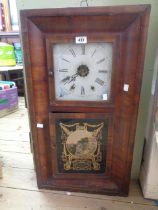 An early 20th Century American walnut cased wall clock with decorative glazed panel door and twin
