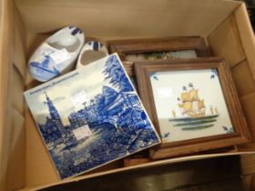 A small box containing three modern framed Dutch Delft tiles, two clogs and another unframed tile