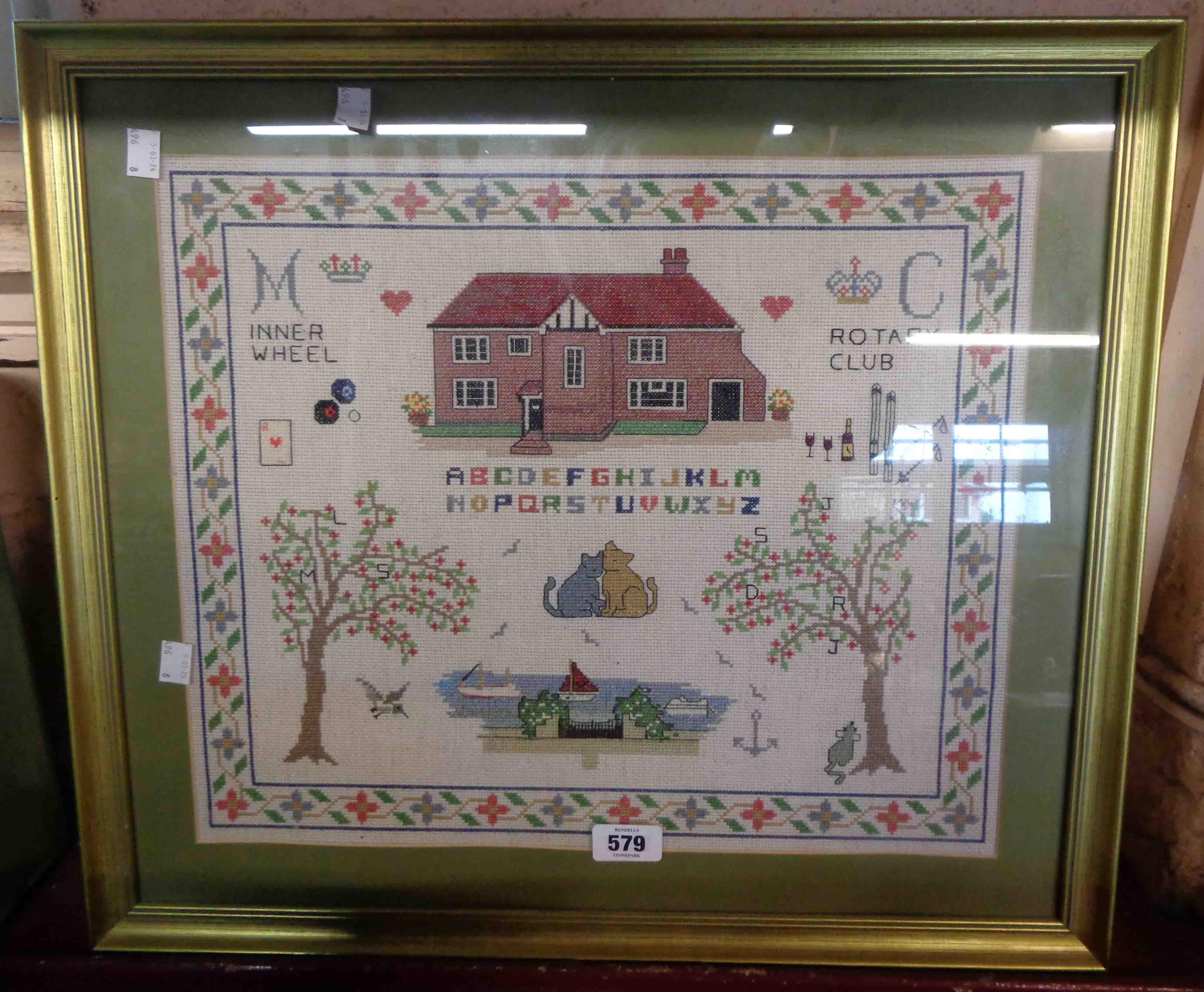 A framed 20th Century Rotary Club (Inner Wheel) sampler with building, trees and text, etc.
