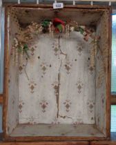 An antique wooden display case with floral arch decoration and paper lining