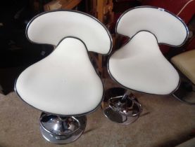 A pair of modern chrome plated framed swivel bar stools with white leatherette upholstery, set on