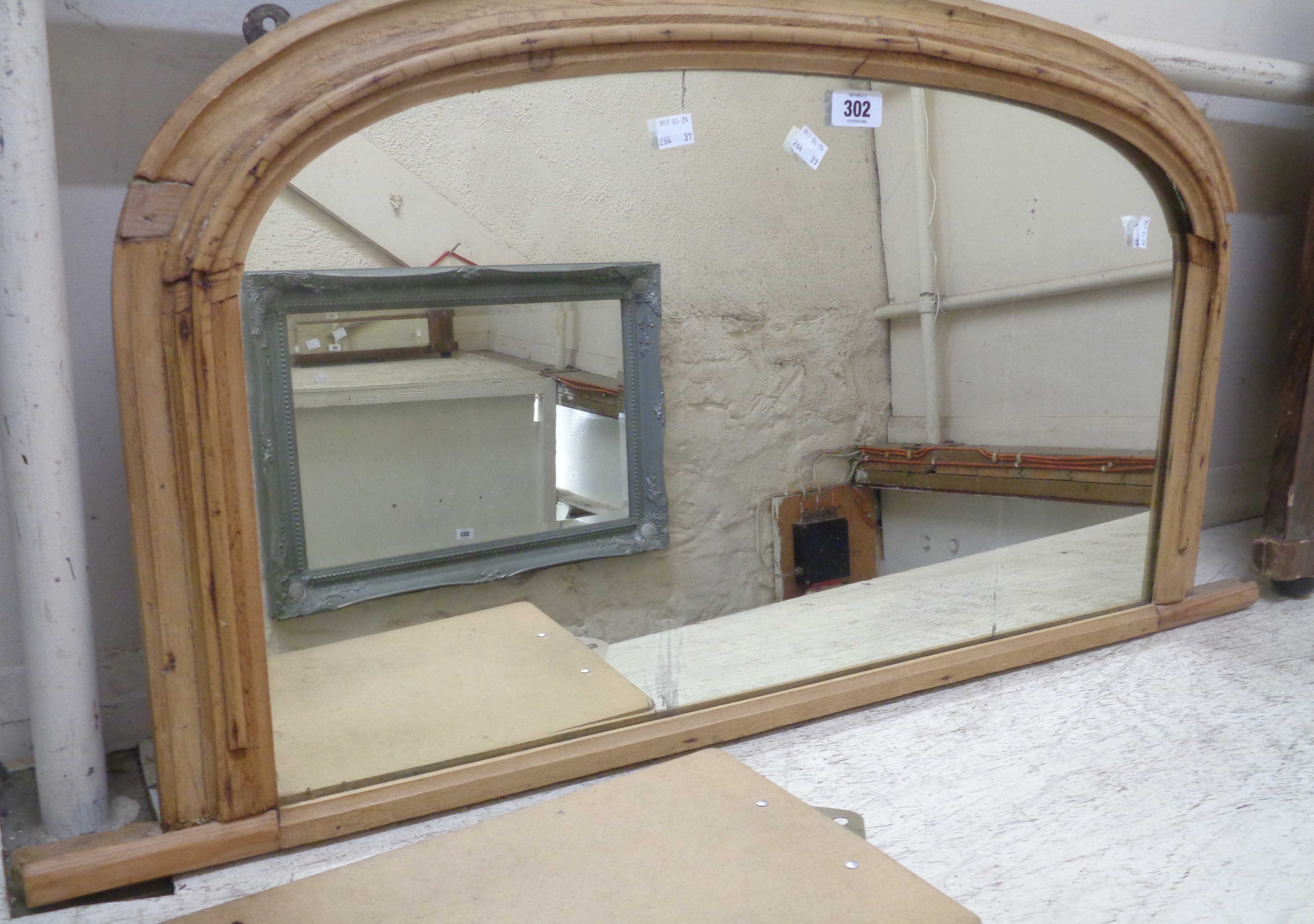 A stripped pine framed overmantel mirror with arched plate