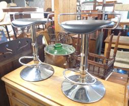 A pair of modern swivel kitchen stools with black leatherette upholstered seats, set on chrome