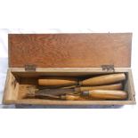 A small wooden box containing five vintage chisels