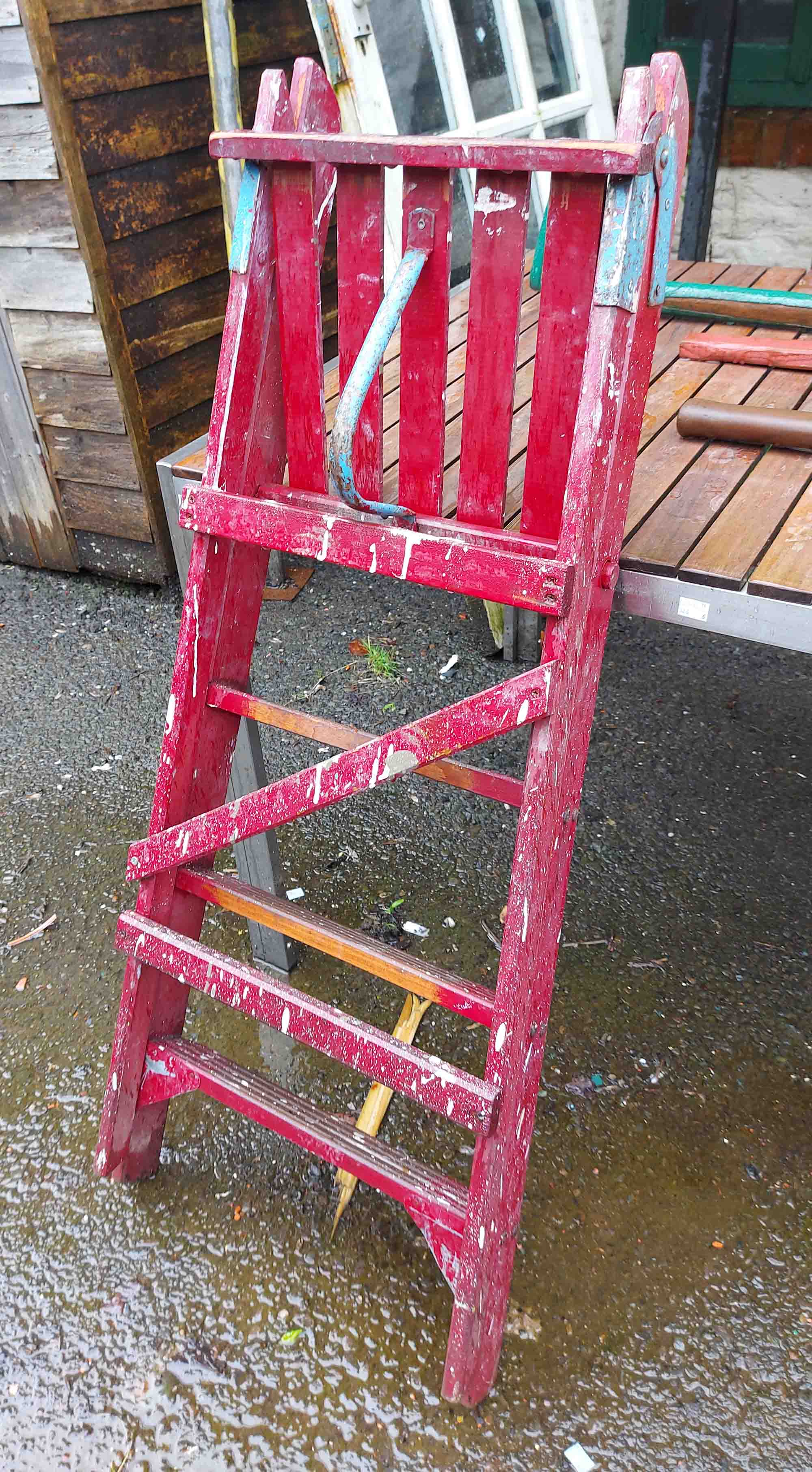 A wooden stepladder with red painted finish