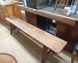 A 1.82m Victorian stained pine chapel pew with solid seat, set on simple supports with metal side