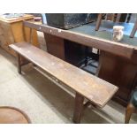 A 1.82m Victorian stained pine chapel pew with solid seat, set on simple supports with metal side