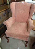 A vintage Parker Knoll wingback armchair with pink tapestry upholstery, set on cabriole front legs