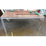 A modern metal garden table with slated wooden top