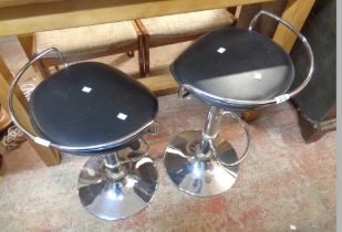 A pair of modern swivel kitchen stools with black leatherette upholstered seats, set on chrome