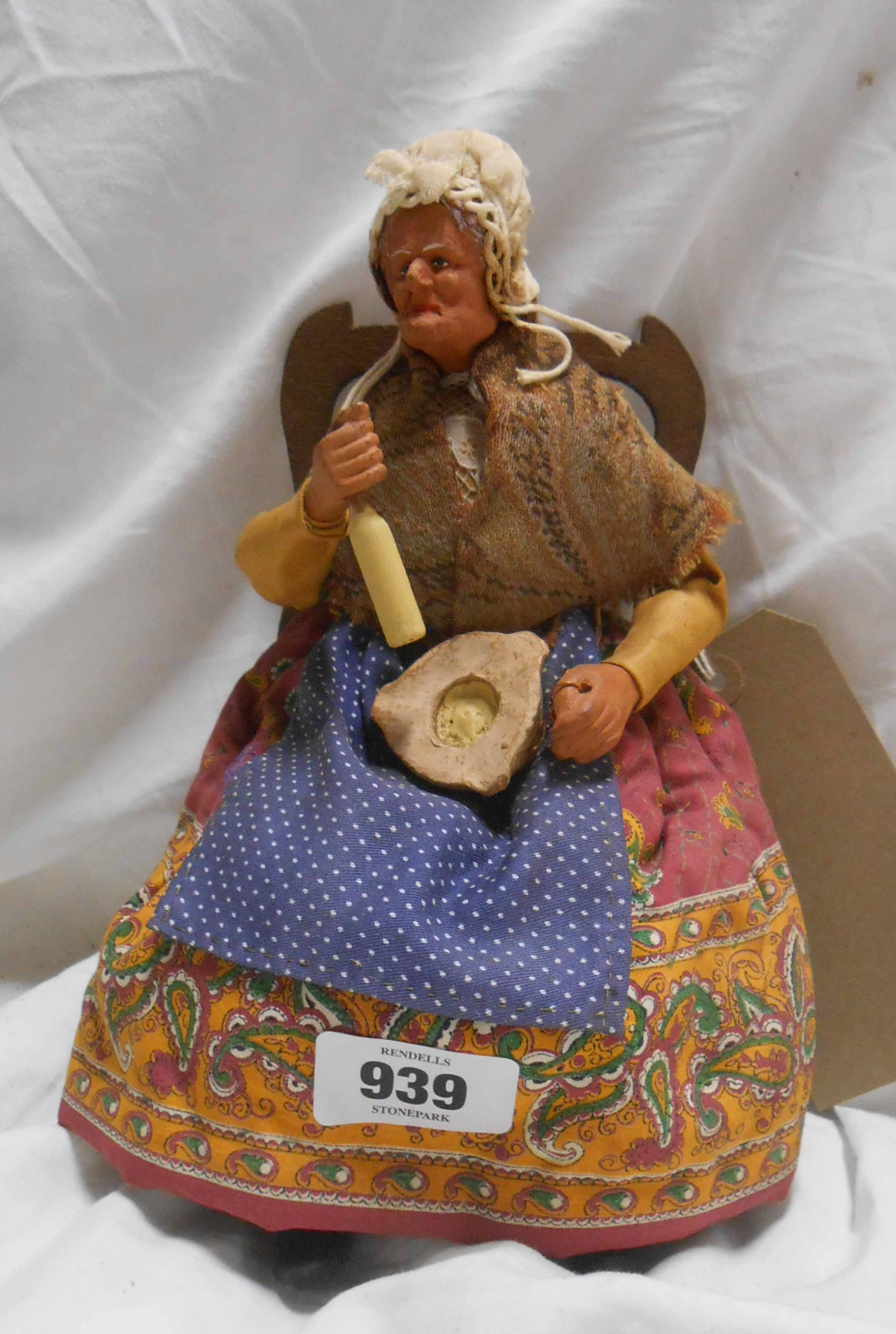 A small vintage figurine of an old lady seated upon a chair