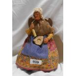 A small vintage figurine of an old lady seated upon a chair