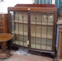 A 1.2m early 20th Century mahogany bow front display cabinet with material lined shelves enclosed by