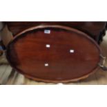 An antique mahogany tray with scalloped rim and brass handle