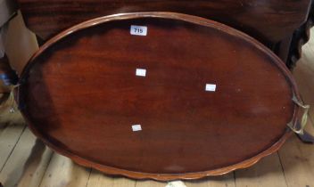 An antique mahogany tray with scalloped rim and brass handle