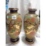 A large pair of Japanese late Satsuma pottery vases with moriage panelled decoration on a blue
