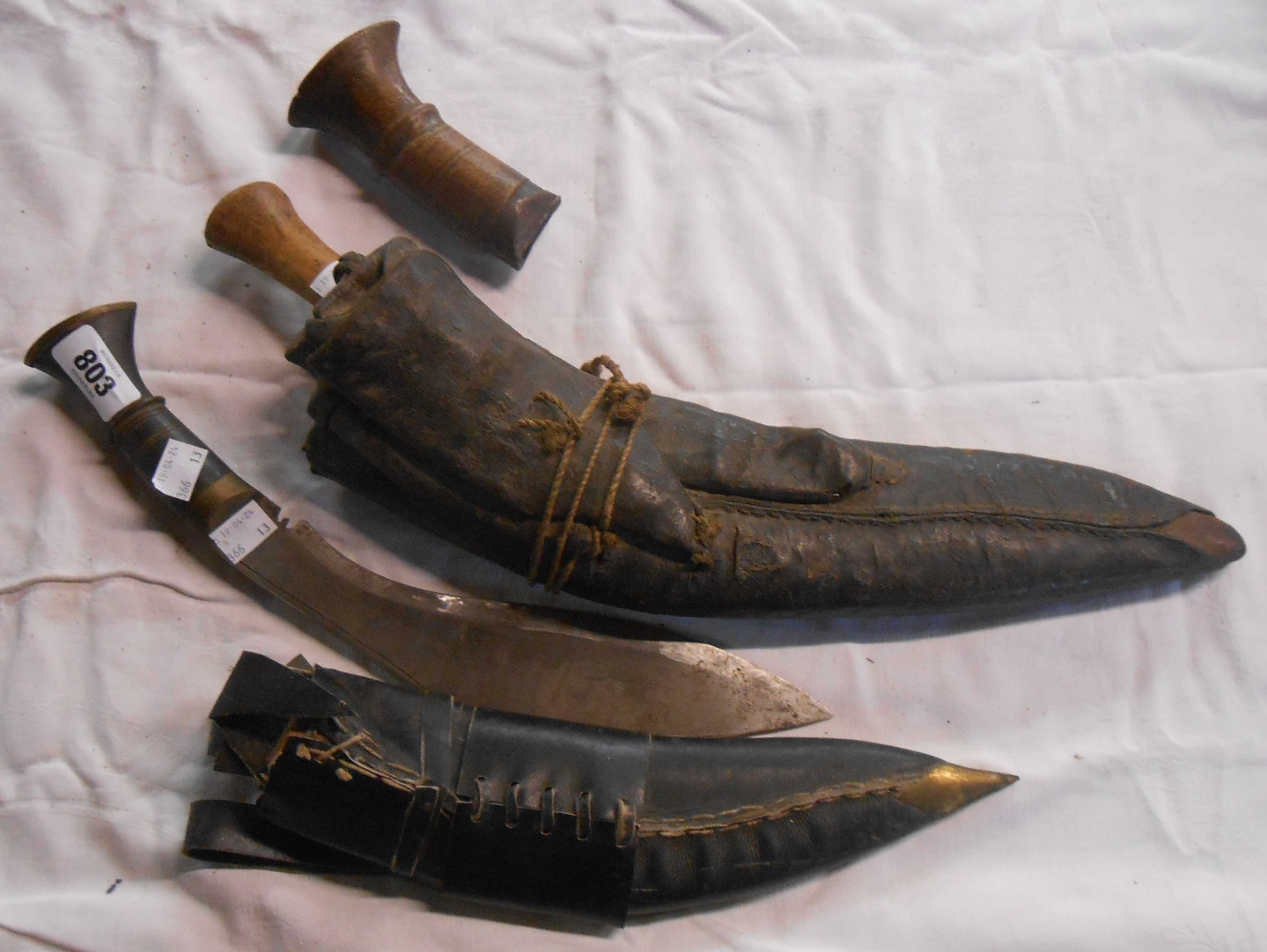 Two old Kukri with wooden handles and leather sheaths - one a/f