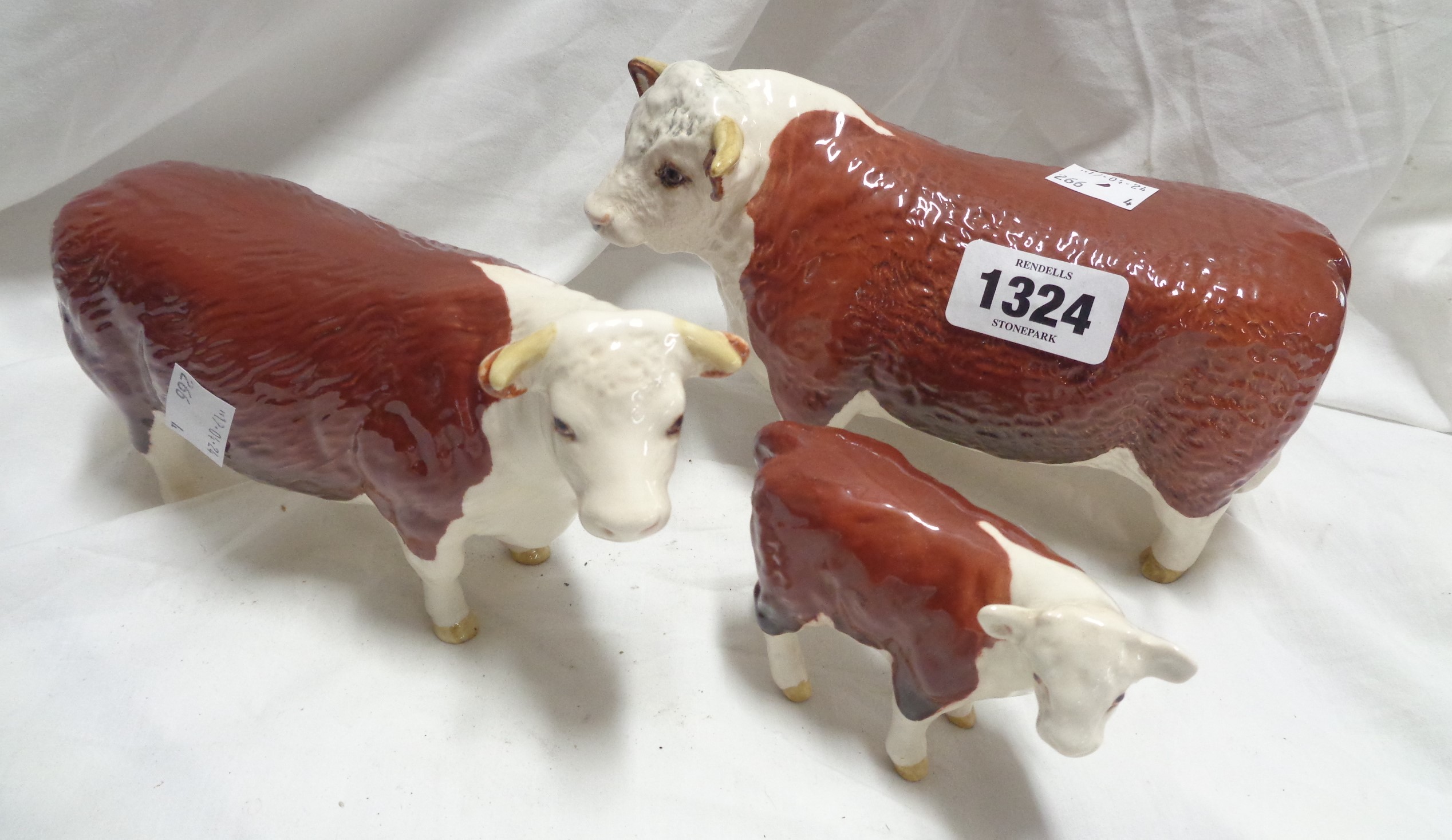 A Beswick pottery Hereford Champion of Champions cattle family comprising bull, cow and calf