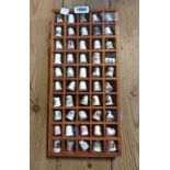 A small wooden display shelf containing a quantity of ceramic thimbles