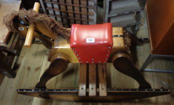 A vintage wooden rocking horse with padded red leather seat