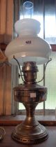 A vintage metal oil lamp with opaque glass shade