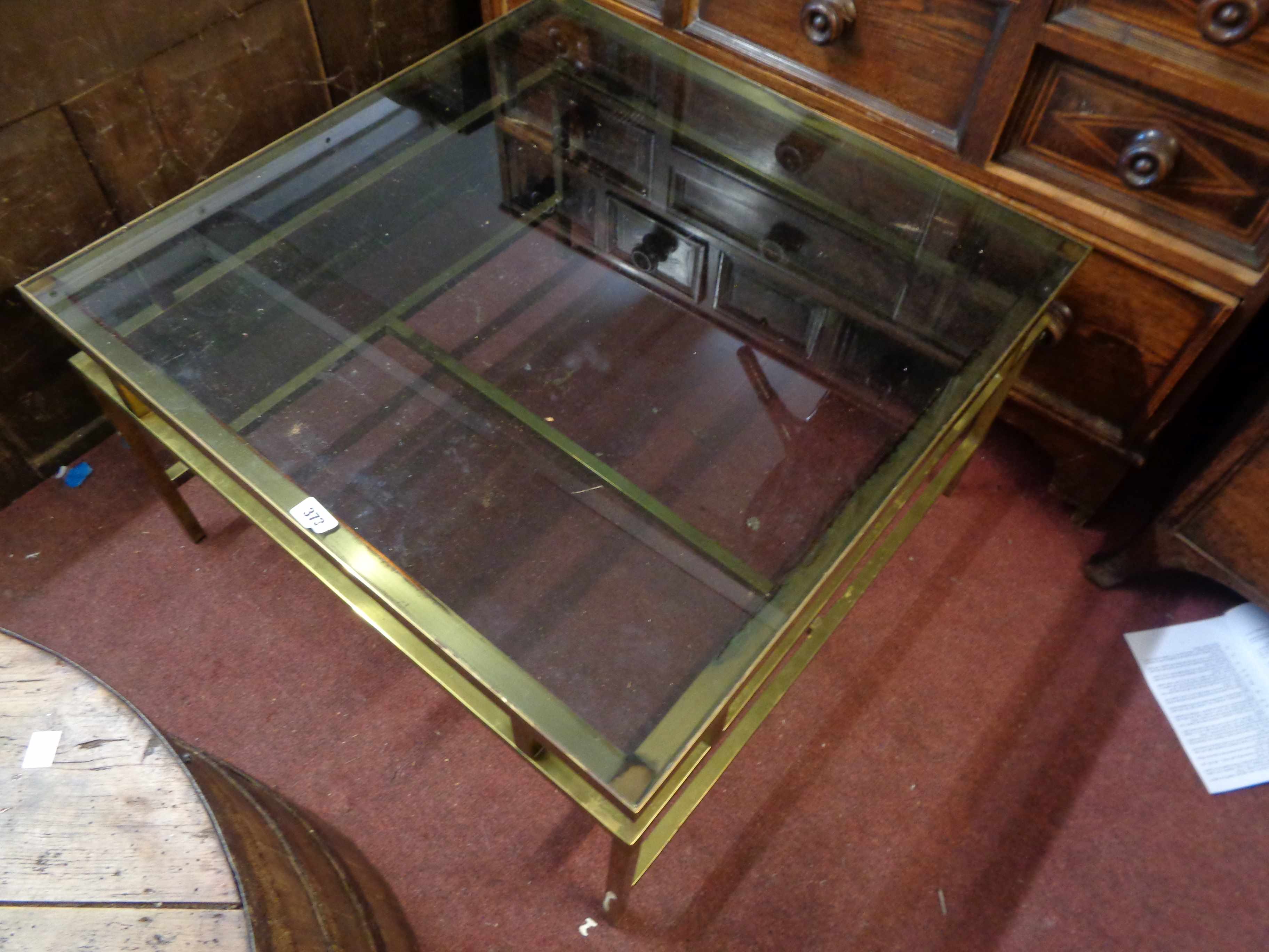 A 77cm mid 20th Century brass framed coffee table with inset smoked glass top, set on square