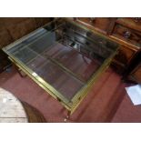 A 77cm mid 20th Century brass framed coffee table with inset smoked glass top, set on square