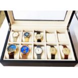 An upholstered perspex topped watch display case containing a collection of eight vintage and modern