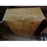 A 74cm modern pine cupboard with panelled door to one side and flight of four drawers to the