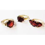 Three 375 (9ct.) gold rings, all set with various garnets comprising a solitairre, three stone and
