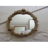 A modern ornate gilt plaster framed oval wall mirror