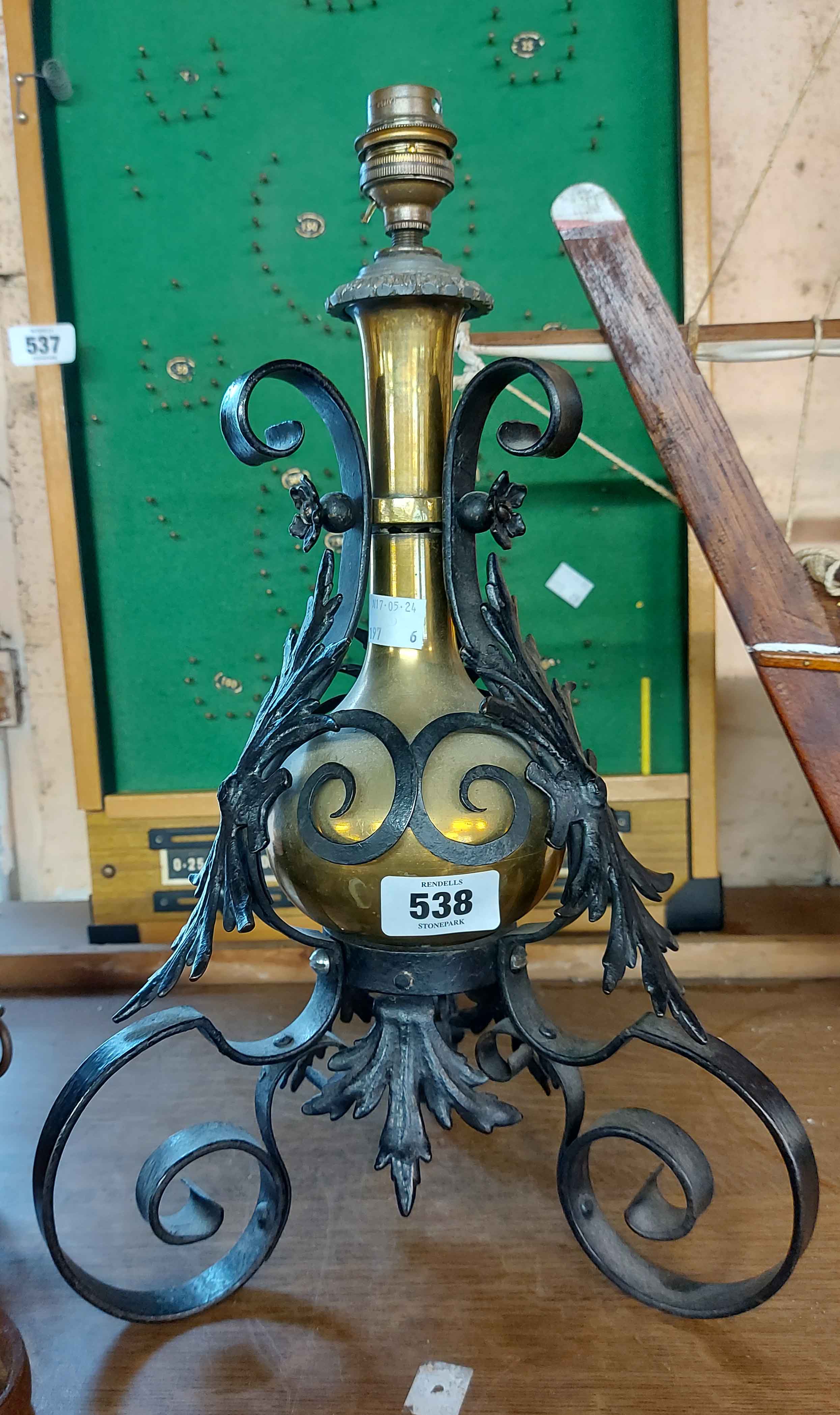 A brass lamp encompassed by a scrolled wrought iron stand