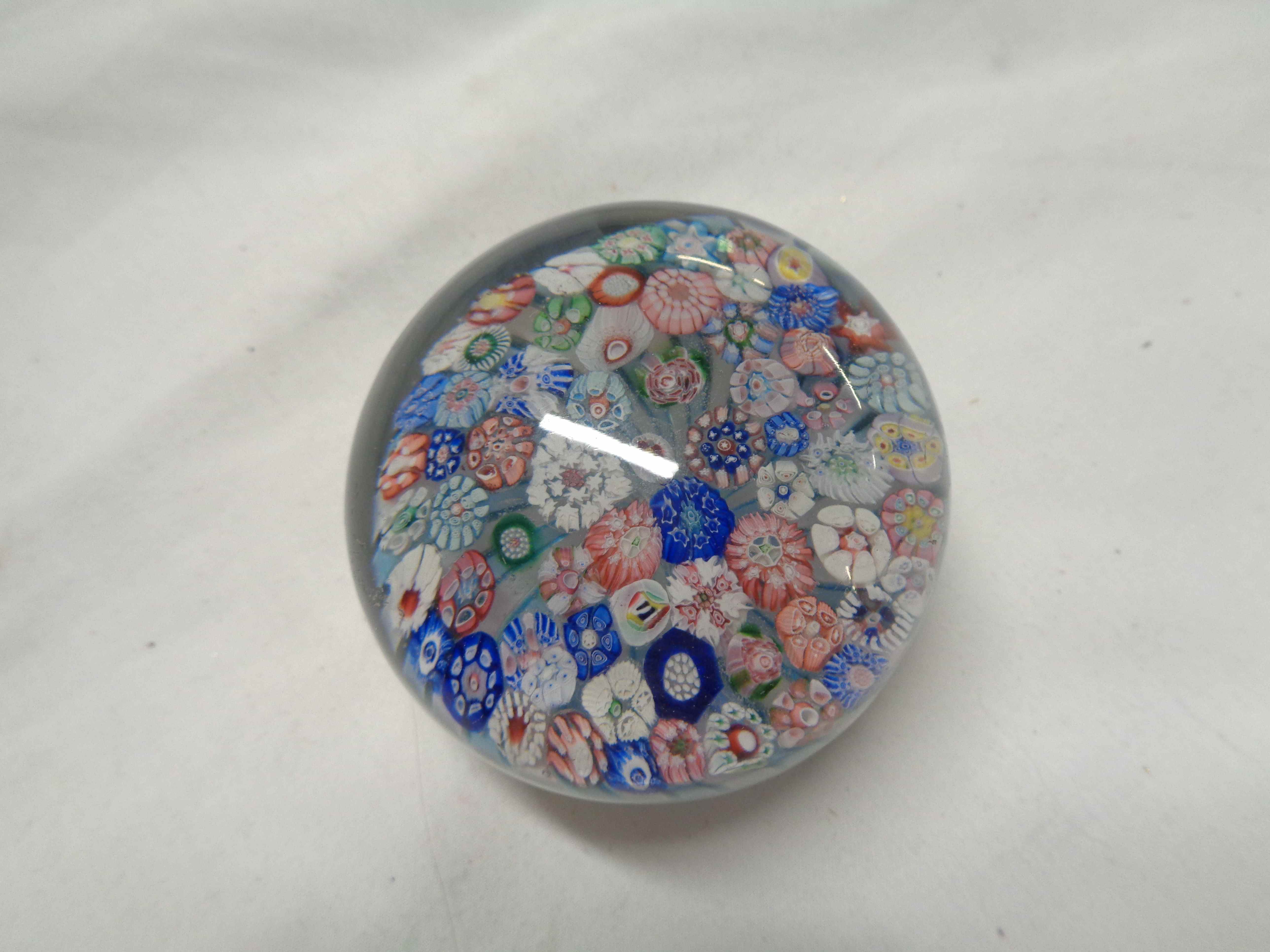 A 19th Century French glass paperweight with millefiori cane decoration on a white and blue swirl