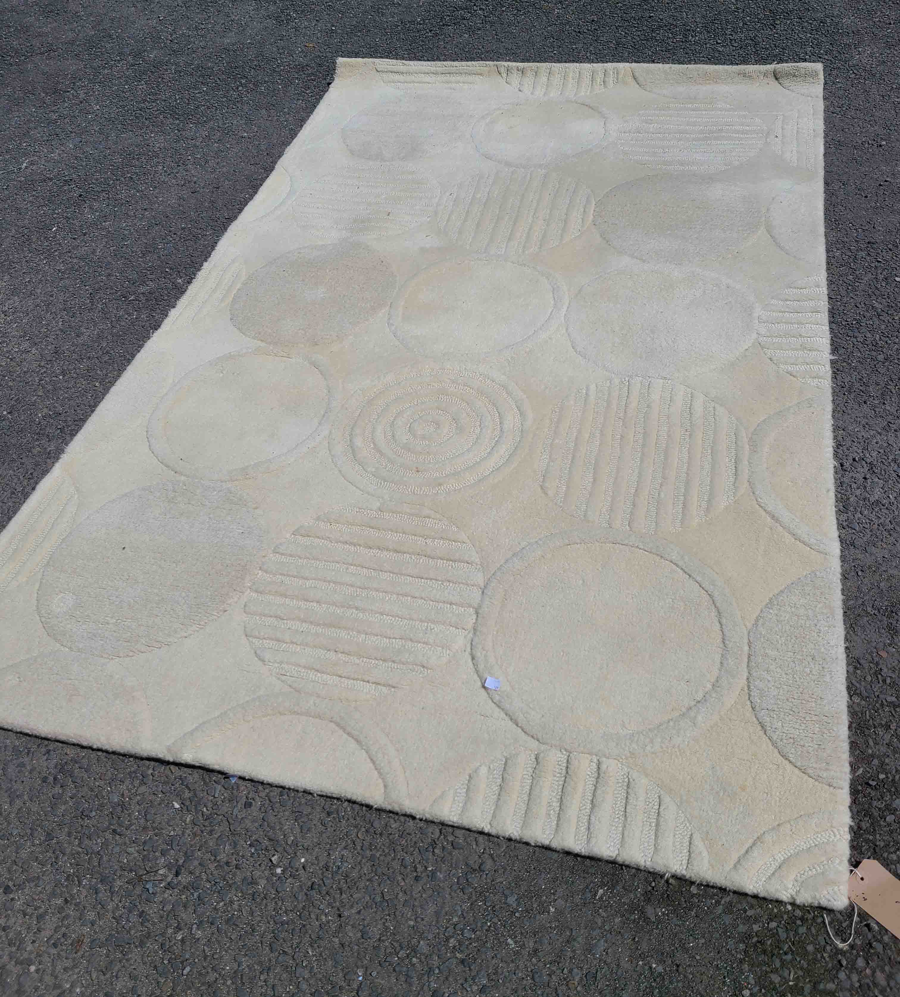 A modern wool rug with circular pattern on white ground