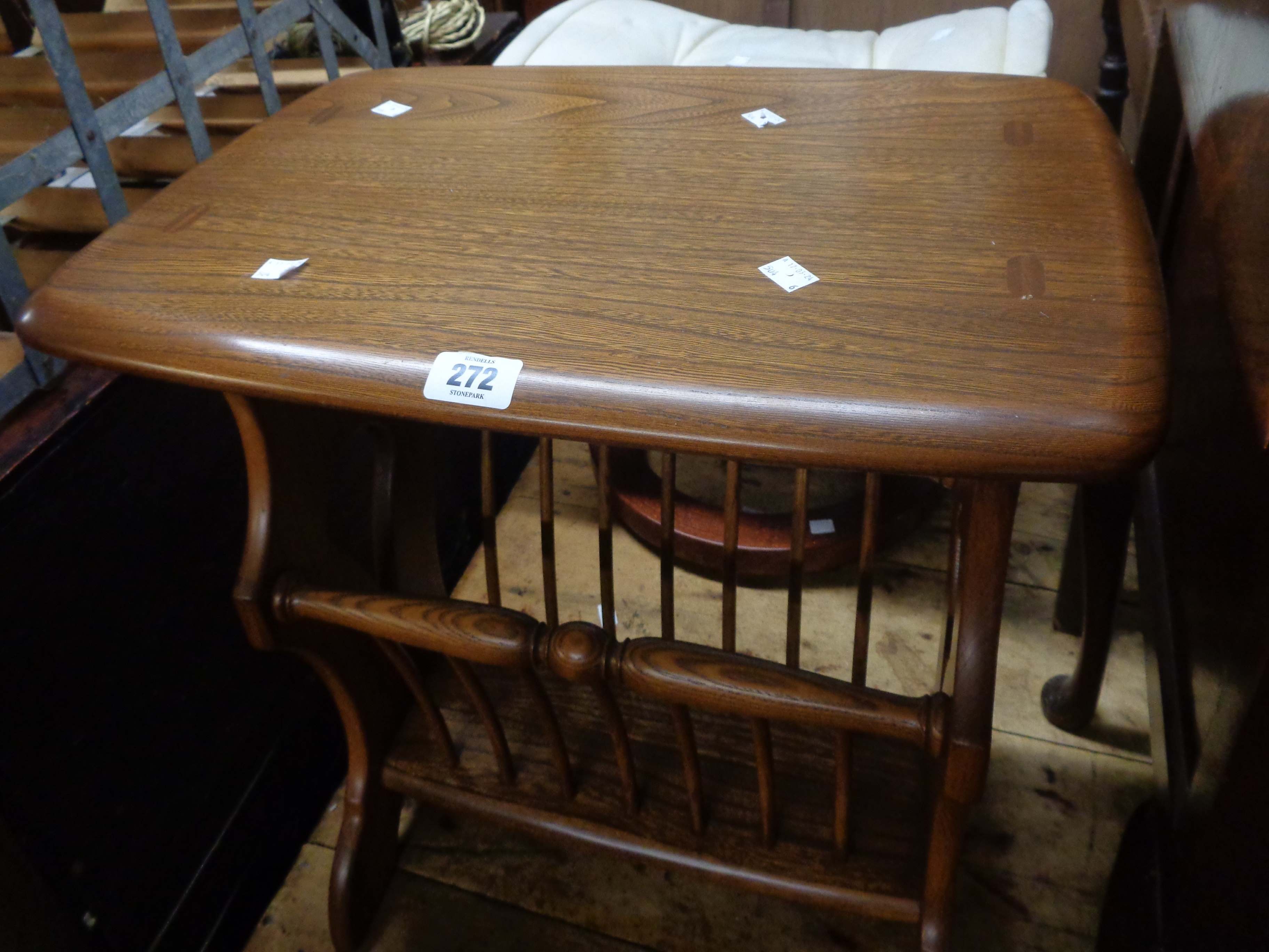 An Ercol dark elm magazine rack with stick dividers, set on pierced standard ends