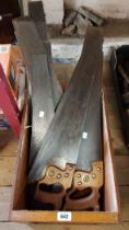 A wooden box containing a quantity of vintage saws including Spear & Jackson, etc.