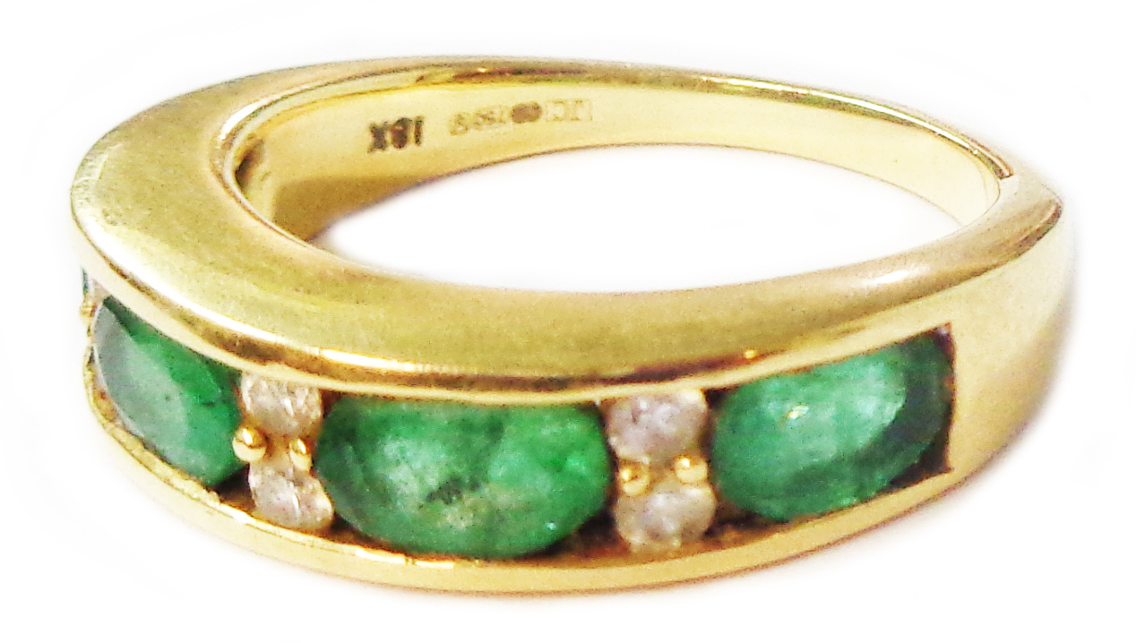 A 750 (18ct.) gold ring with four channel set emeralds interspersed with tiny diamonds - size O 1/2