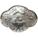 A 31cm silver dressing table tray of lobed form with embossed cherub group and foliate scroll