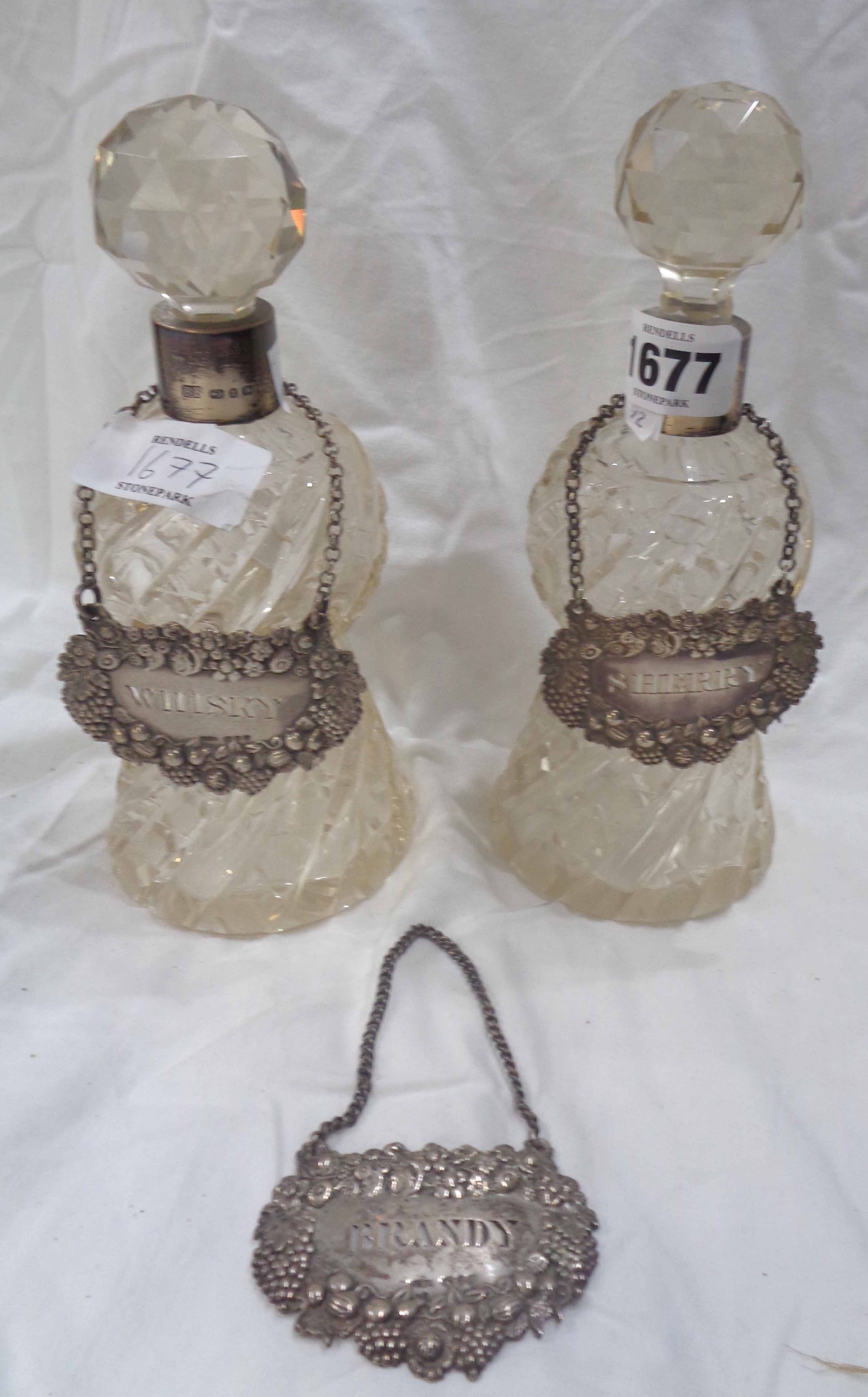 A pair of cut glass small spirit decanters of waisted form with silver collars and faceted