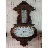 A late Victorian walnut cased banjo barometer/thermometer with carved and pierced decoration and