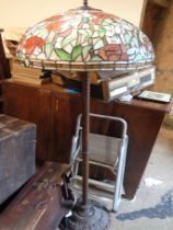 A modern cast metal standard lamp with Tiffany style coloured glass shade, set on wrythen pillar and