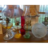 Three glass oil lamps - sold with and opaque shade and a ruby glass chimney