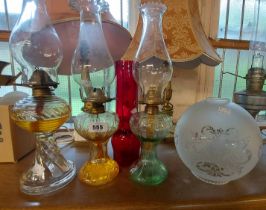 Three glass oil lamps - sold with and opaque shade and a ruby glass chimney