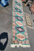 A modern Shirvana natural jute fibre handmade runner with repeat medallion decoration on a green